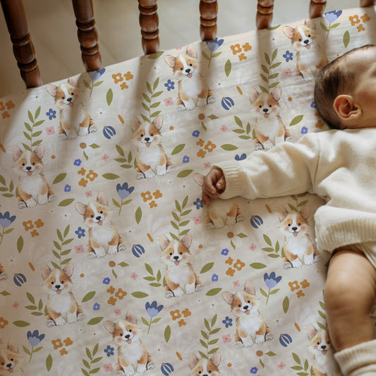 Baby lying on a crib sheet with corgi and floral pattern
