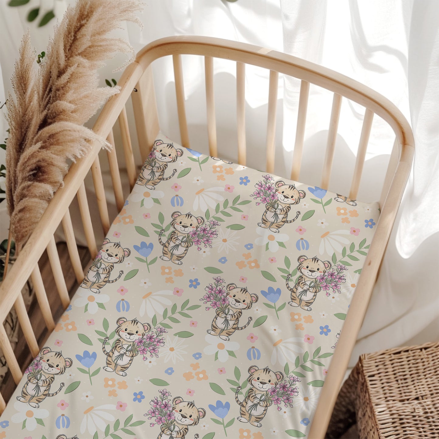 Crib with a decorative sheet featuring cartoon tigers and flowers, surrounded by pampas grass and white curtains.