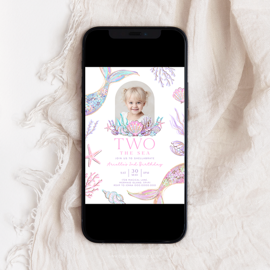 Phone displaying a birthday invitation with mermaid design on a white fabric background