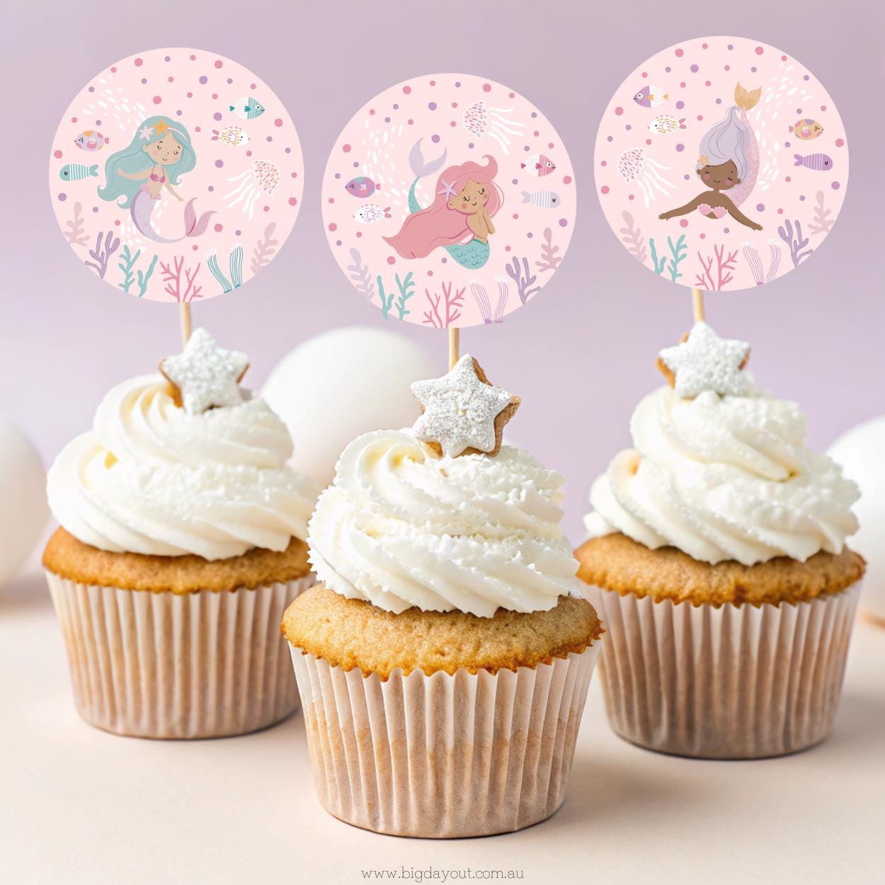 Cupcakes with mermaid-themed toppers on a light purple background