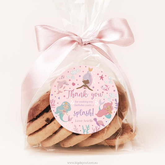 Packaged cookies with a pink ribbon and mermaid-themed label on a white background
