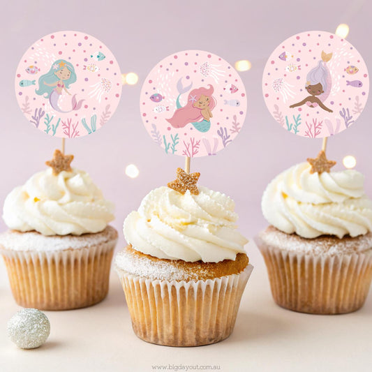 Cupcakes with mermaid-themed toppers on a light pink background
