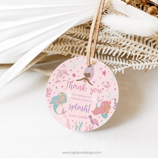 Round pink tag with mermaid design and text on a white background