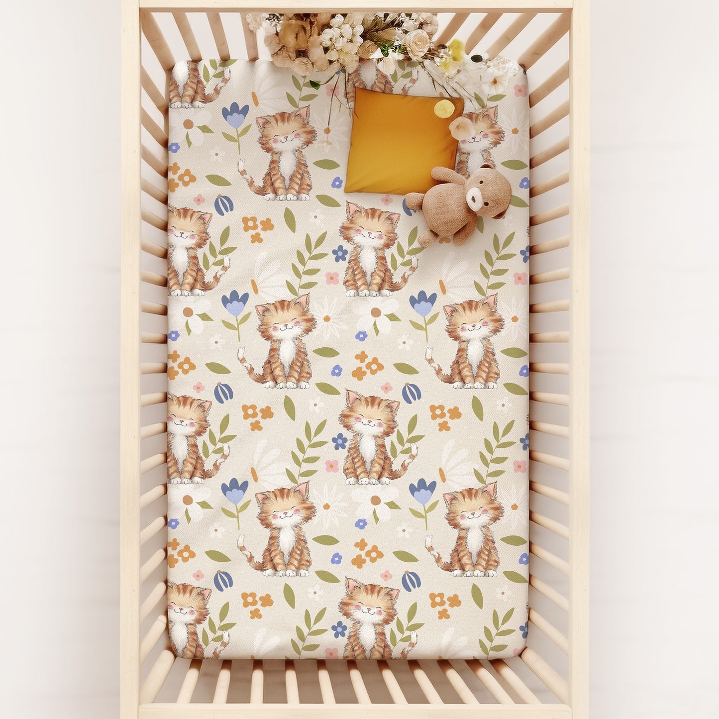 Crib with a floral cottagecore cat patterned sheet on a white background