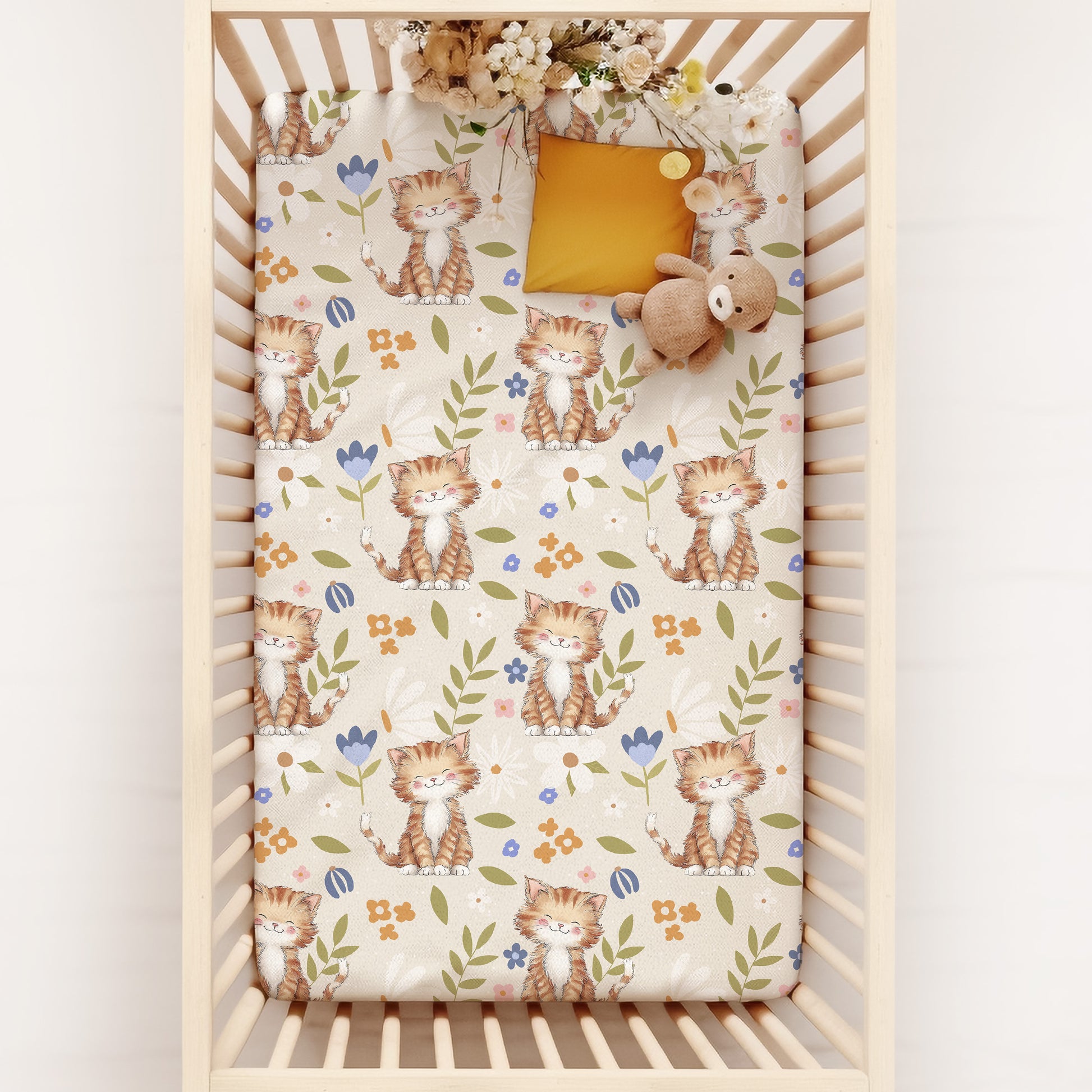 Crib with a floral cottagecore cat patterned sheet on a white background