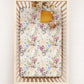 Crib with a floral and australian animal-patterned sheet featuring kangaroos and koalas
