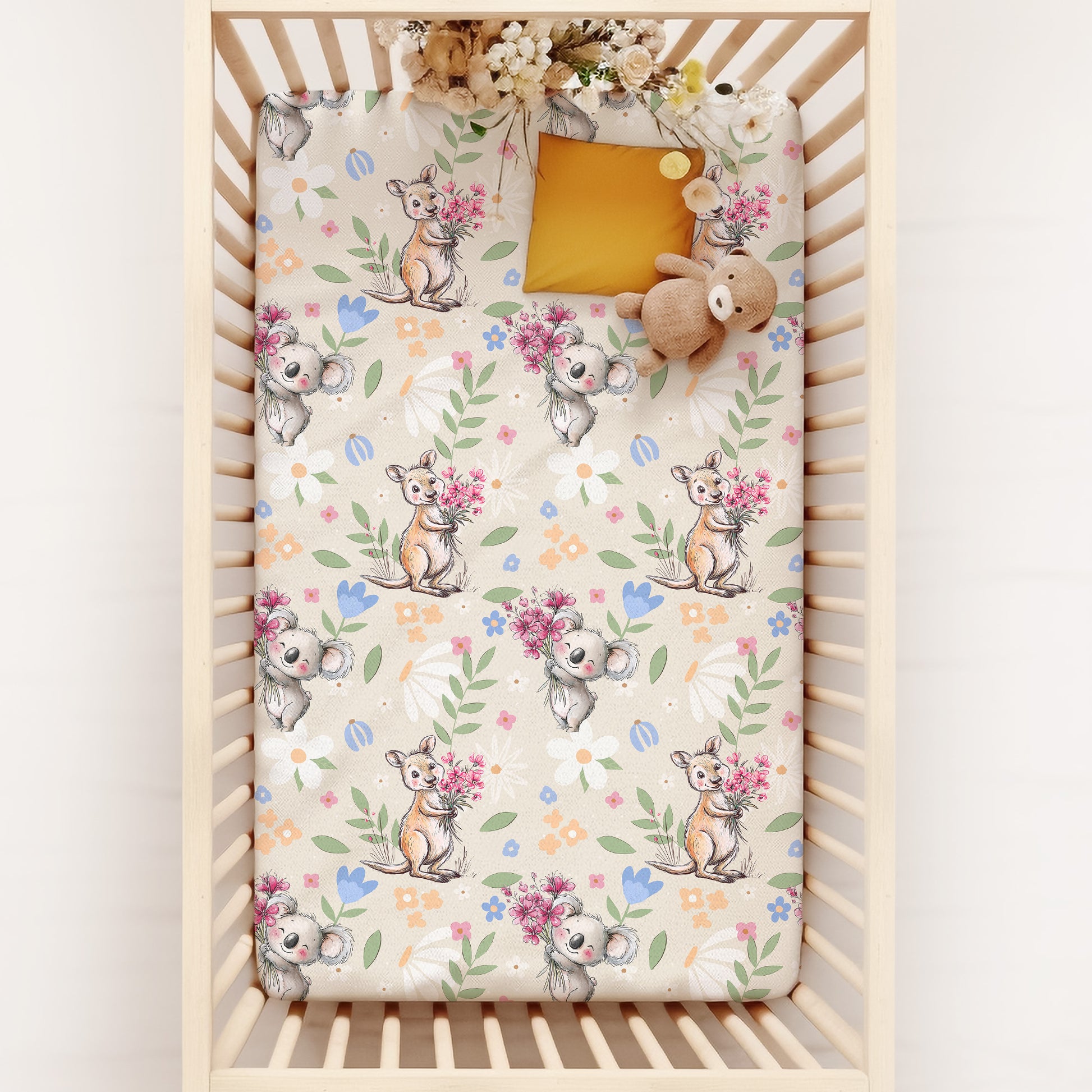 Crib with a floral and australian animal-patterned sheet featuring kangaroos and koalas