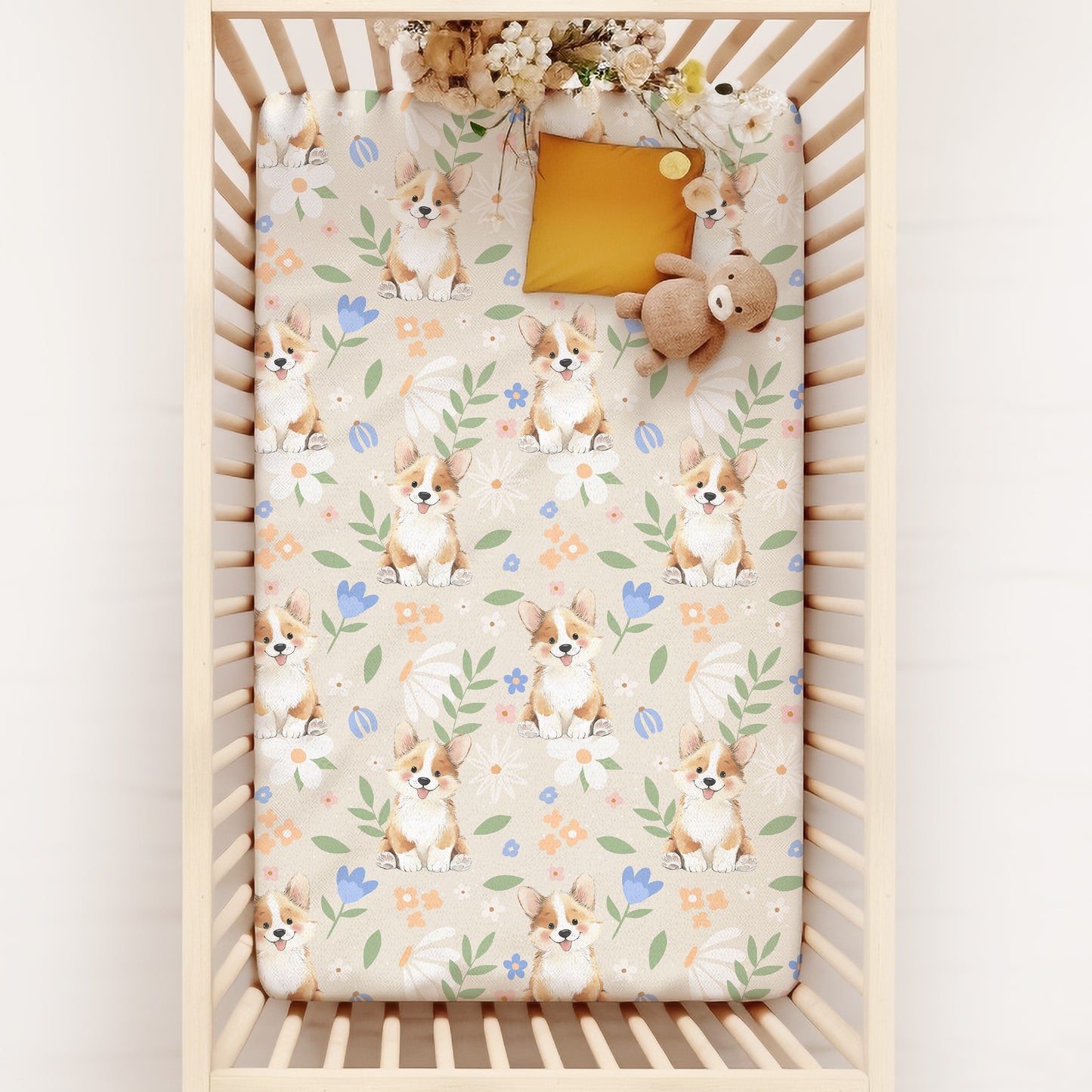Crib with a patterned sheet featuring pastel florals and cute corgi puppies on a white background