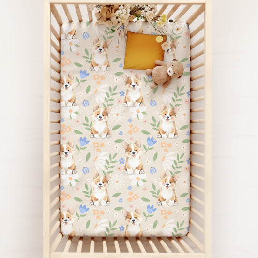 Crib with a patterned sheet featuring pastel florals and cute corgi puppies on a white background