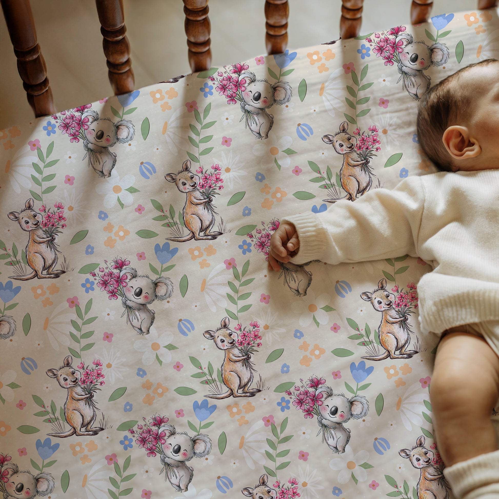 Baby lying on a crib sheet with koala and kangaroo designs and flowers