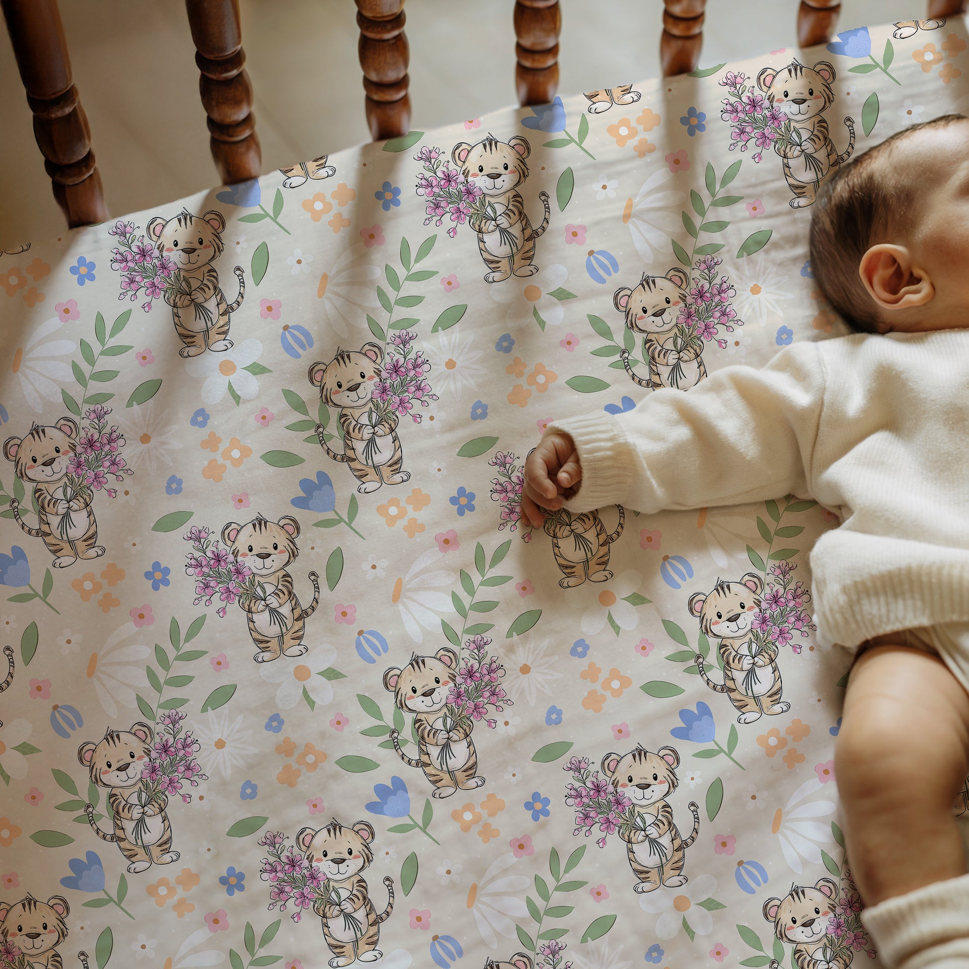 Baby lying on a crib with a baby tiger and flower patterned sheet.