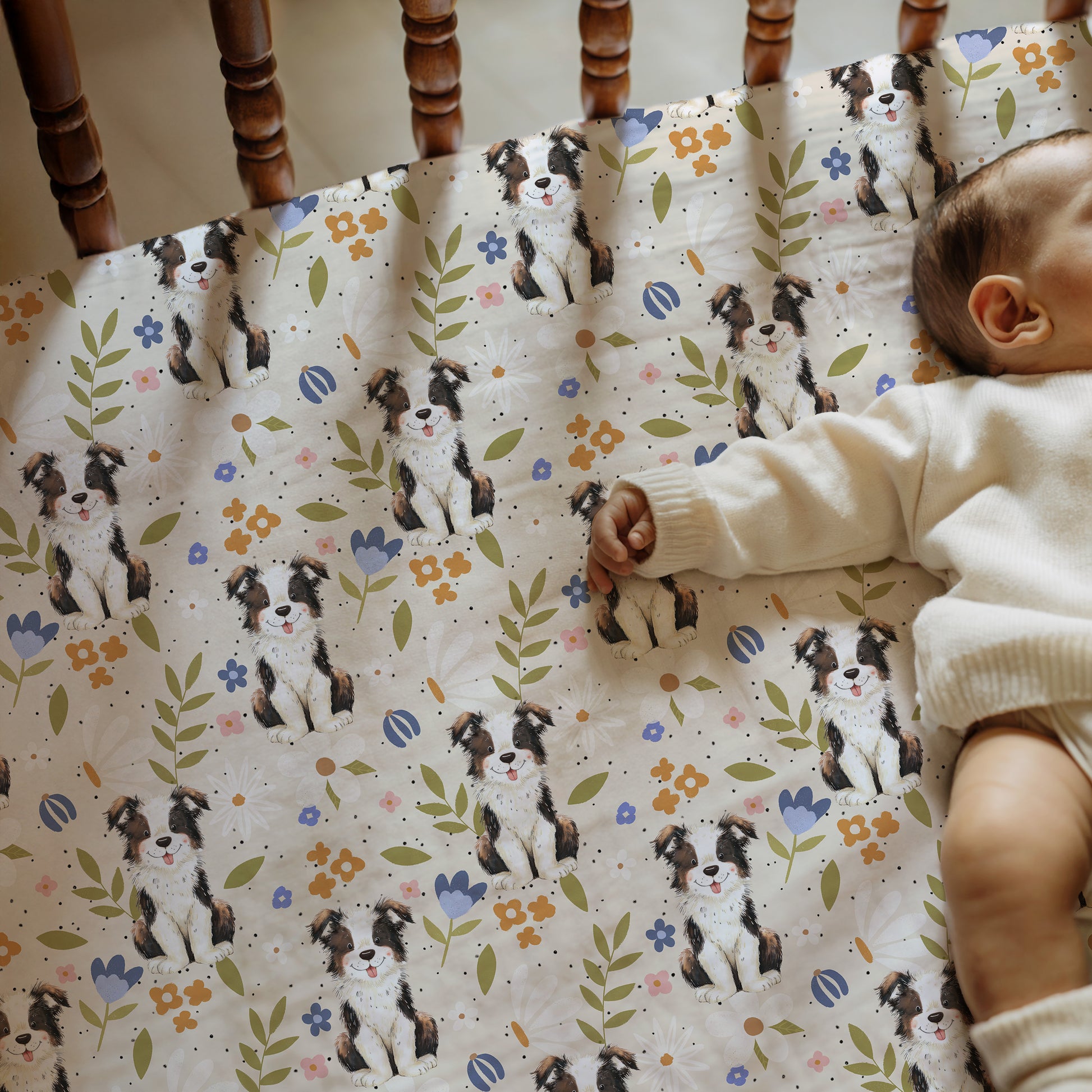 Baby lying on a crib with a patterned sheet featuring dogs and flowers.