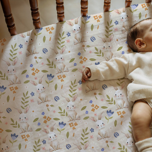 Baby lying on a crib mattress with a bunny and floral pattern