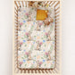 Crib with a floral-patterned mattress cover featuring kangaroo and flowers.