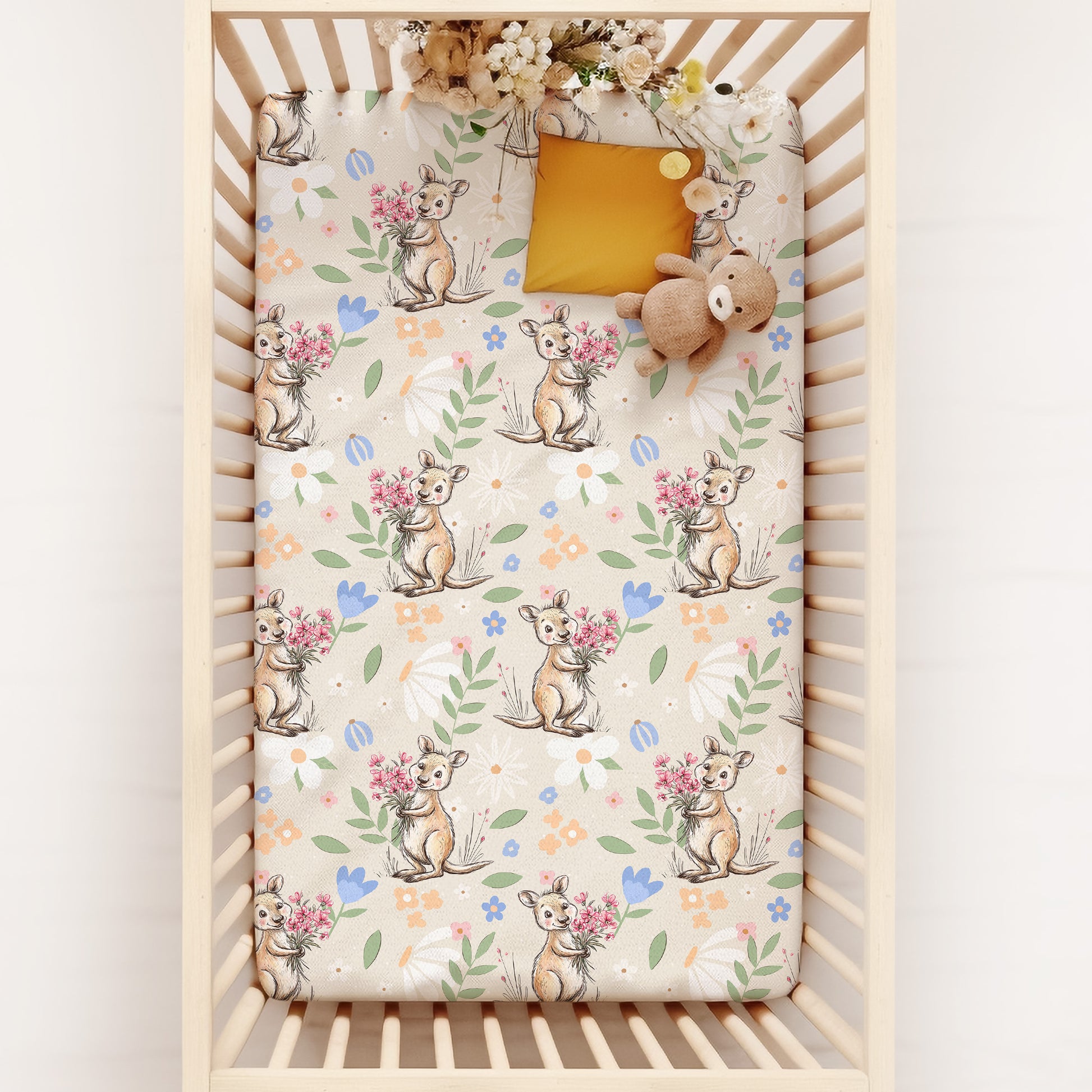 Crib with a floral-patterned mattress cover featuring kangaroo and flowers.