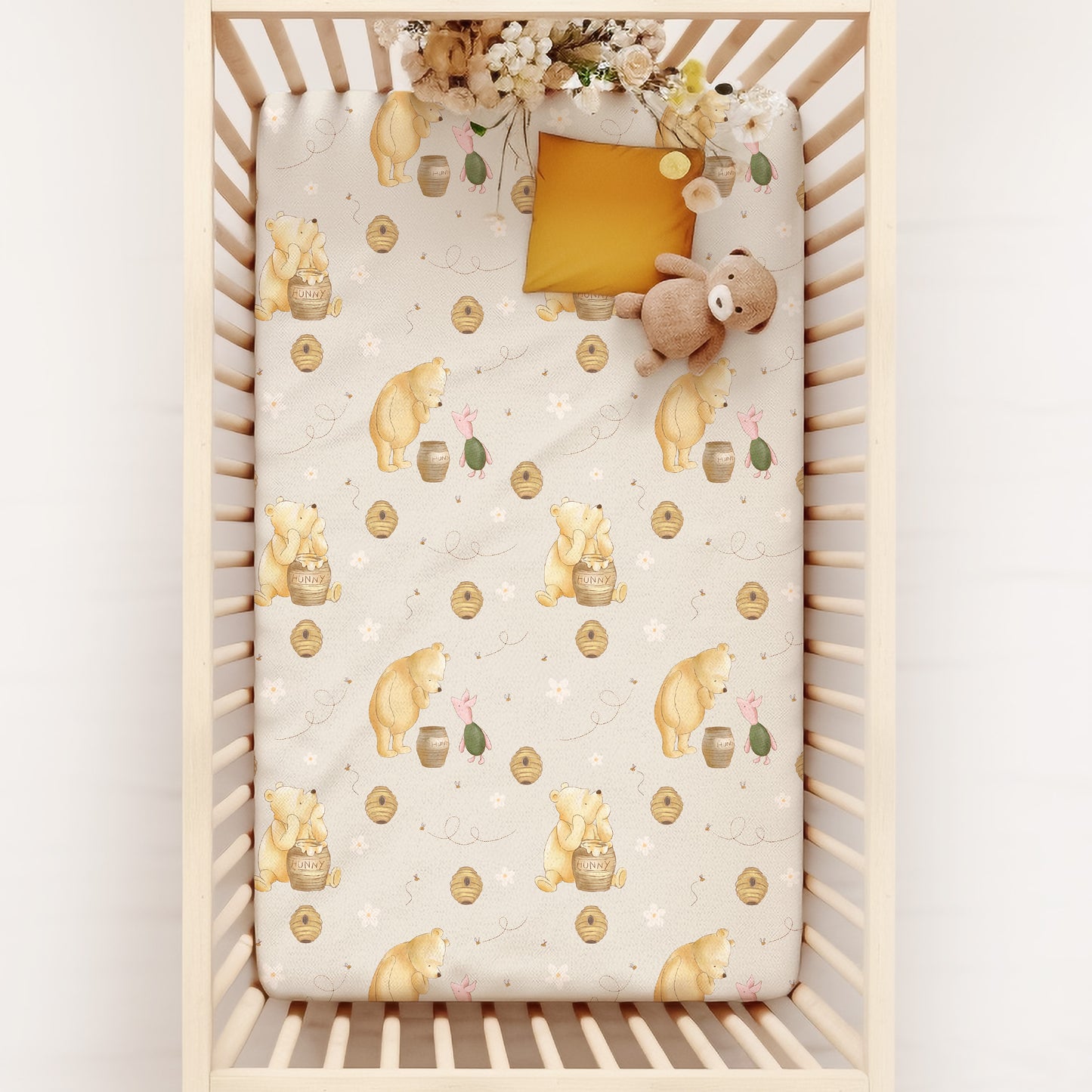 Crib with a patterned sheet featuring classic winnie the pooh and piglet on a white background