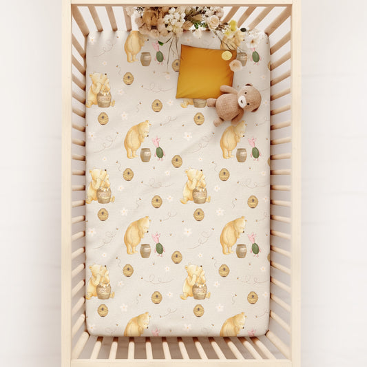 Crib with a patterned sheet featuring classic winnie the pooh and piglet on a white background
