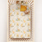 Crib with a patterned sheet featuring pooh bear and flowers on a white background