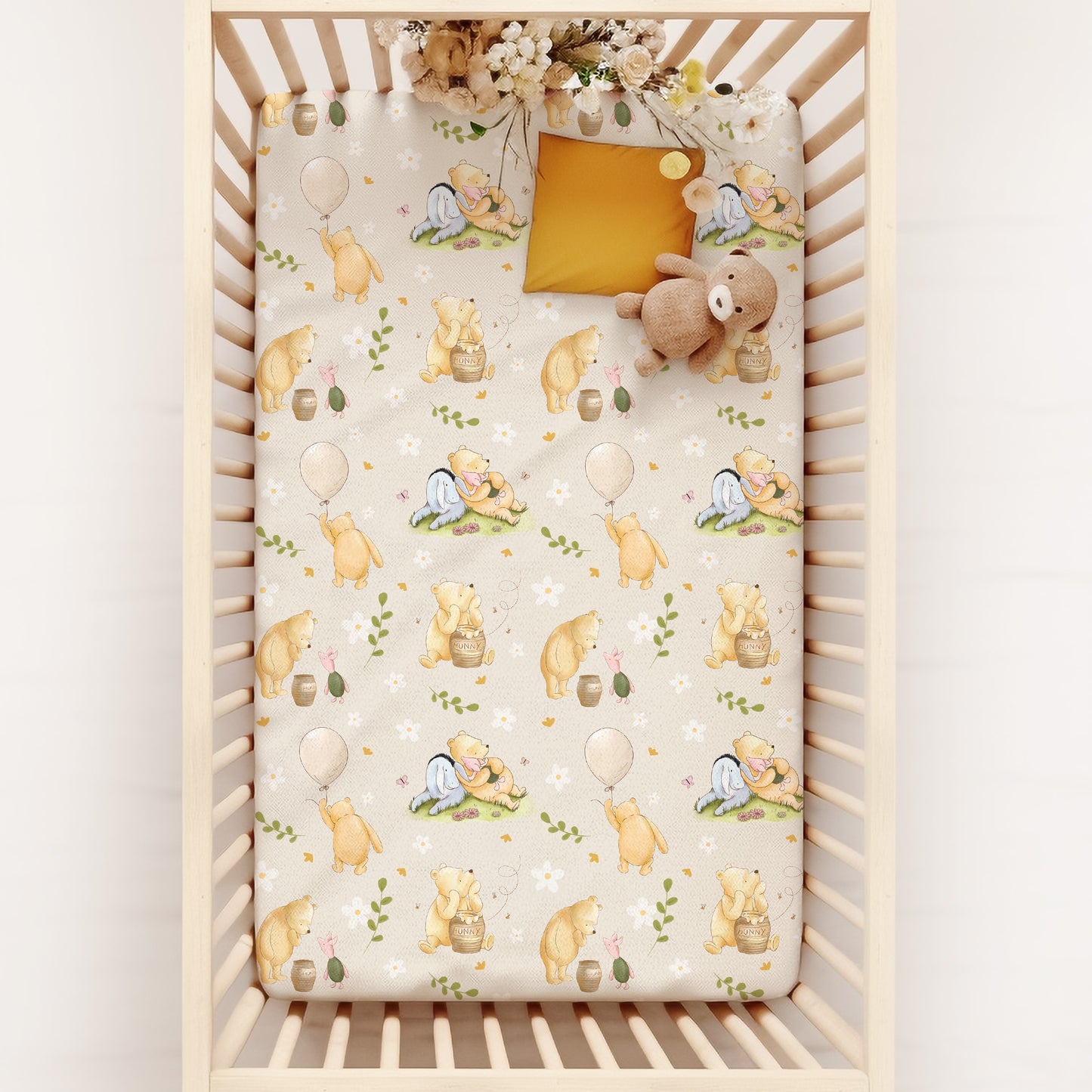 Crib with a patterned sheet featuring pooh bear and flowers on a white background