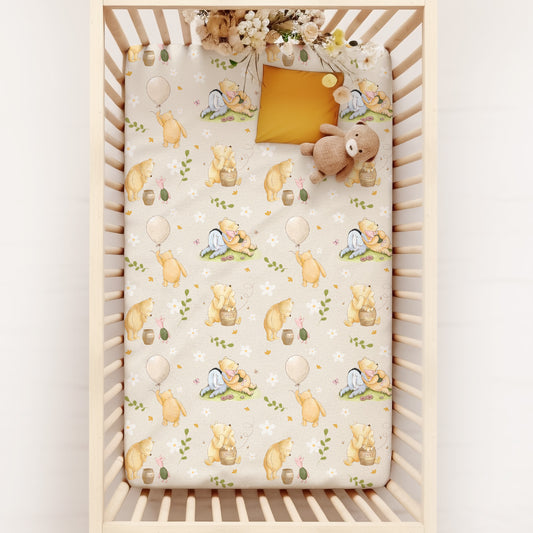 Crib with a patterned sheet featuring pooh bear and flowers on a white background