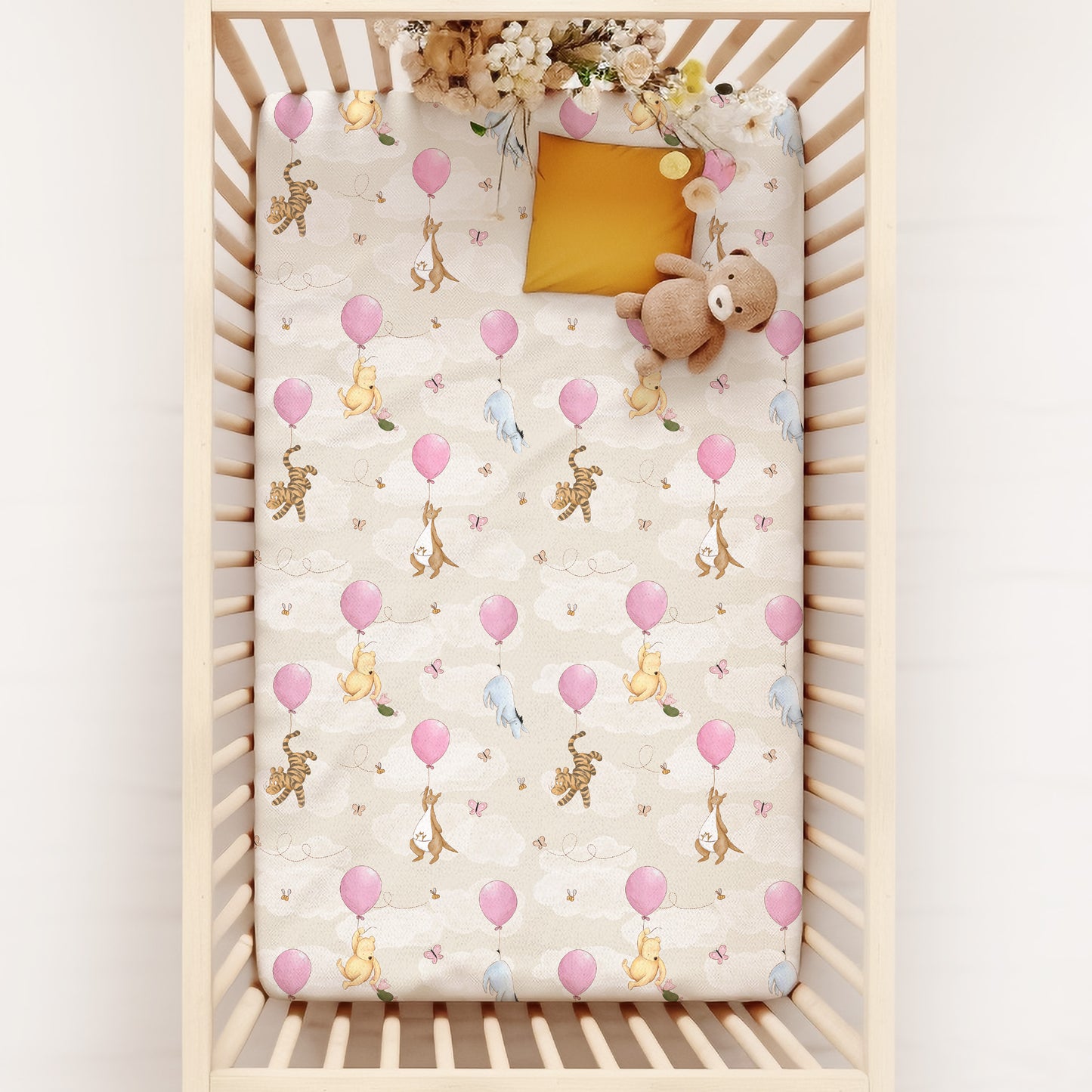 Crib with a decorative sheet featuring classic winnie the pooh and friends hanging onto balloons in the clouds on a white background