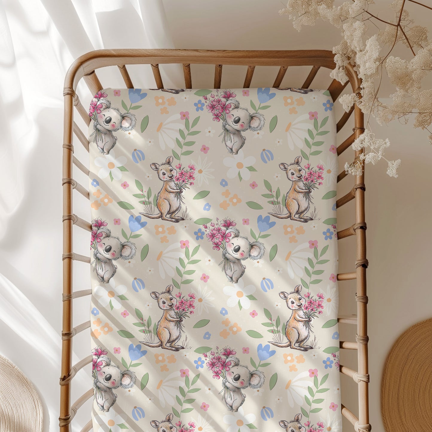 Crib with a decorative sheet featuring koala and kangaroo illustrations and flowers.