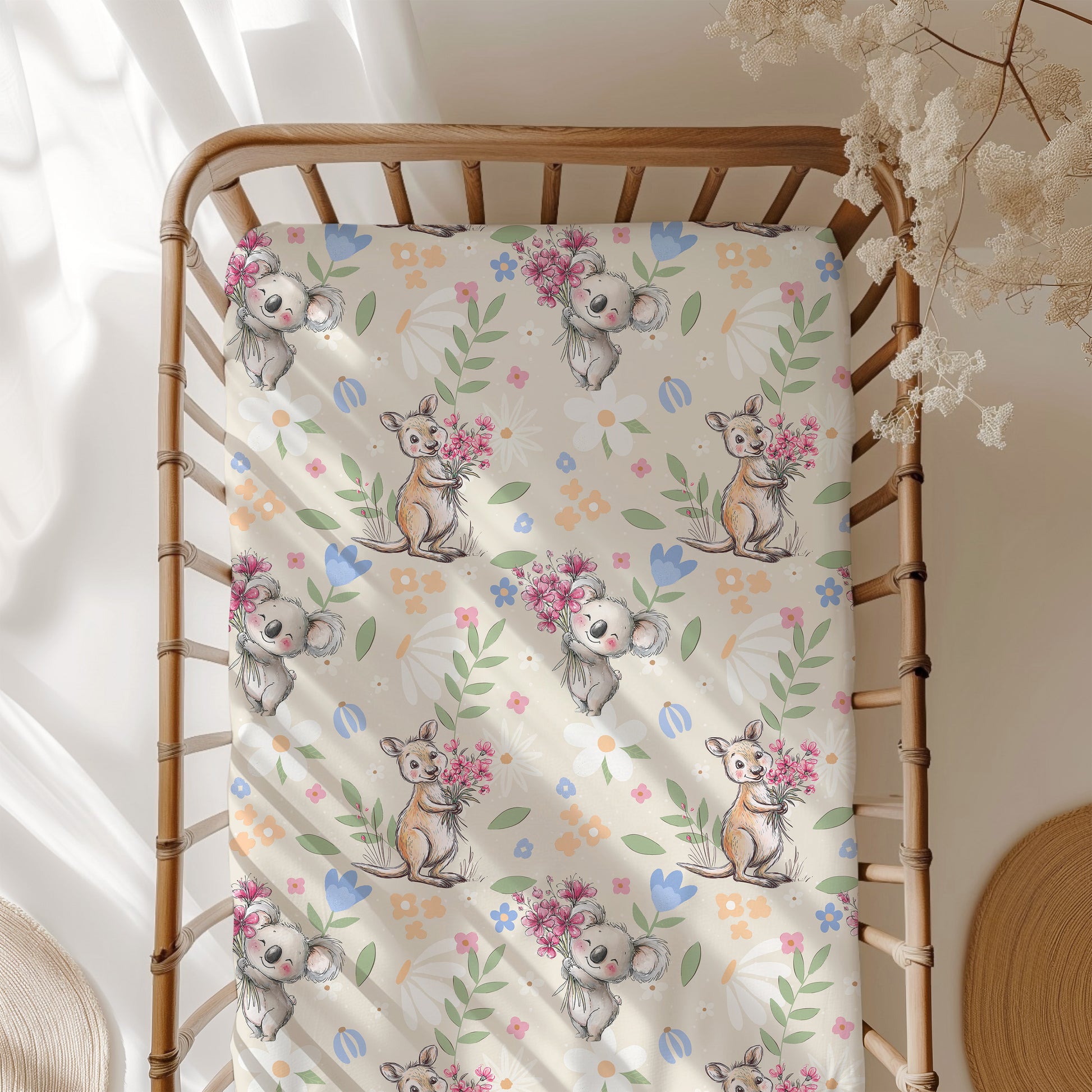 Crib with a decorative sheet featuring koala and kangaroo illustrations and flowers.