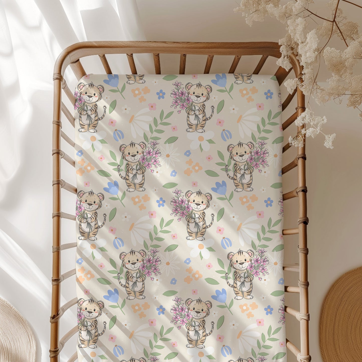 Crib with a patterned sheet featuring cartoon tigers and flowers.