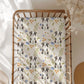 Blanket with dog pattern draped over a wooden crib in a softly lit room.