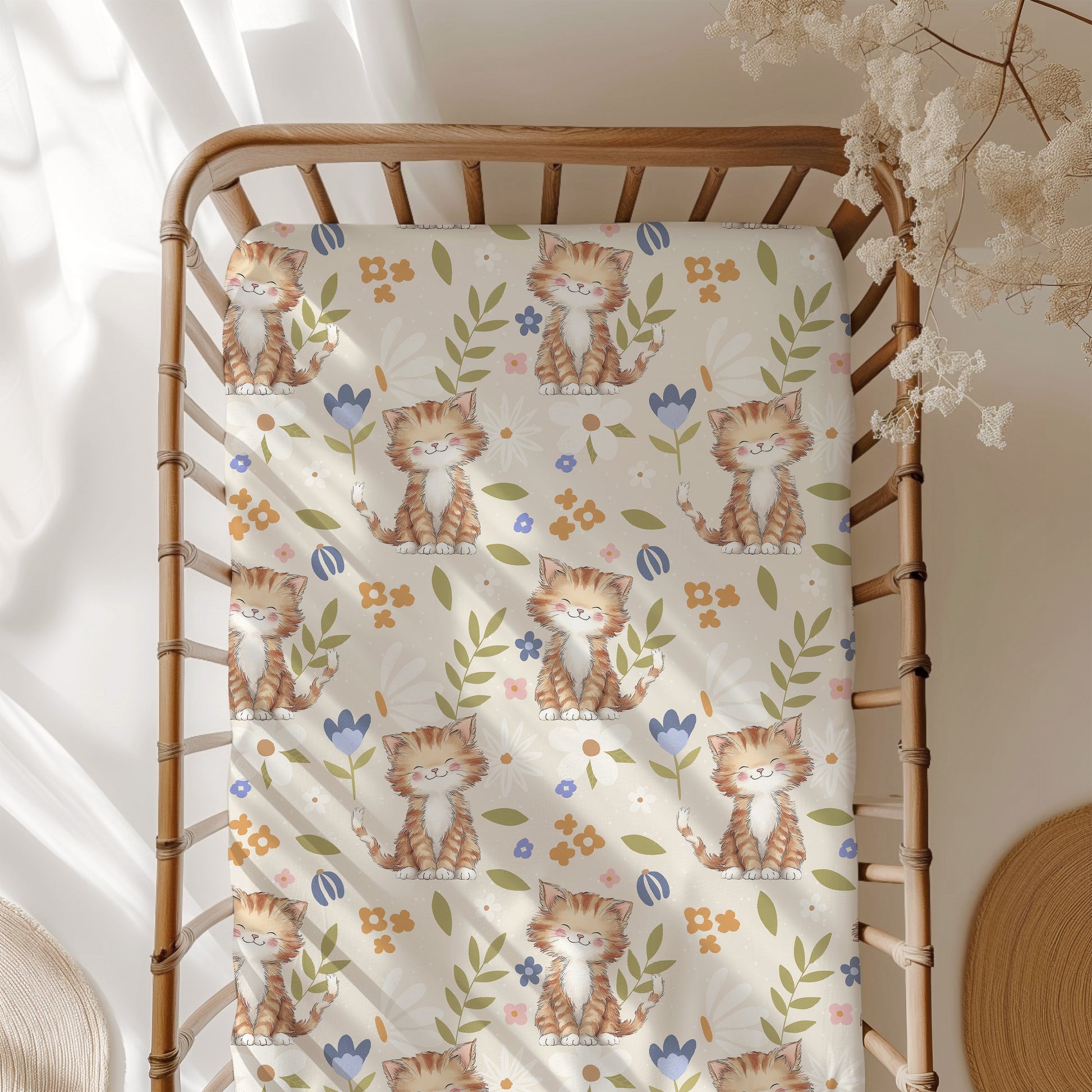 Crib with a patterned sheet featuring cartoon cats and flowers.