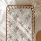 Crib sheet with koala and floral pattern on a wooden crib