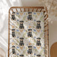 Crib with a decorative blanket featuring rottweiler puppies and floral patterns.