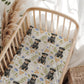 Crib with a floral patterned sheet featuring illustrations of dogs and flowers.