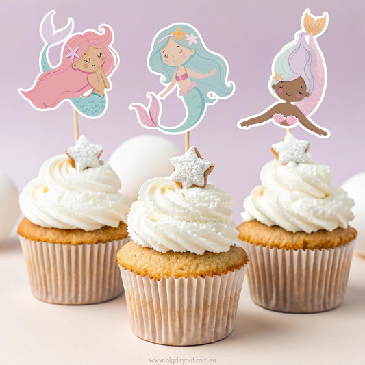 Cupcakes with mermaid-themed toppers on a light purple background