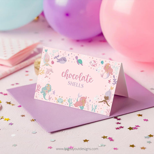 Card with mermaid design and 'chocolate shells' text on a pink background with balloons and confetti.